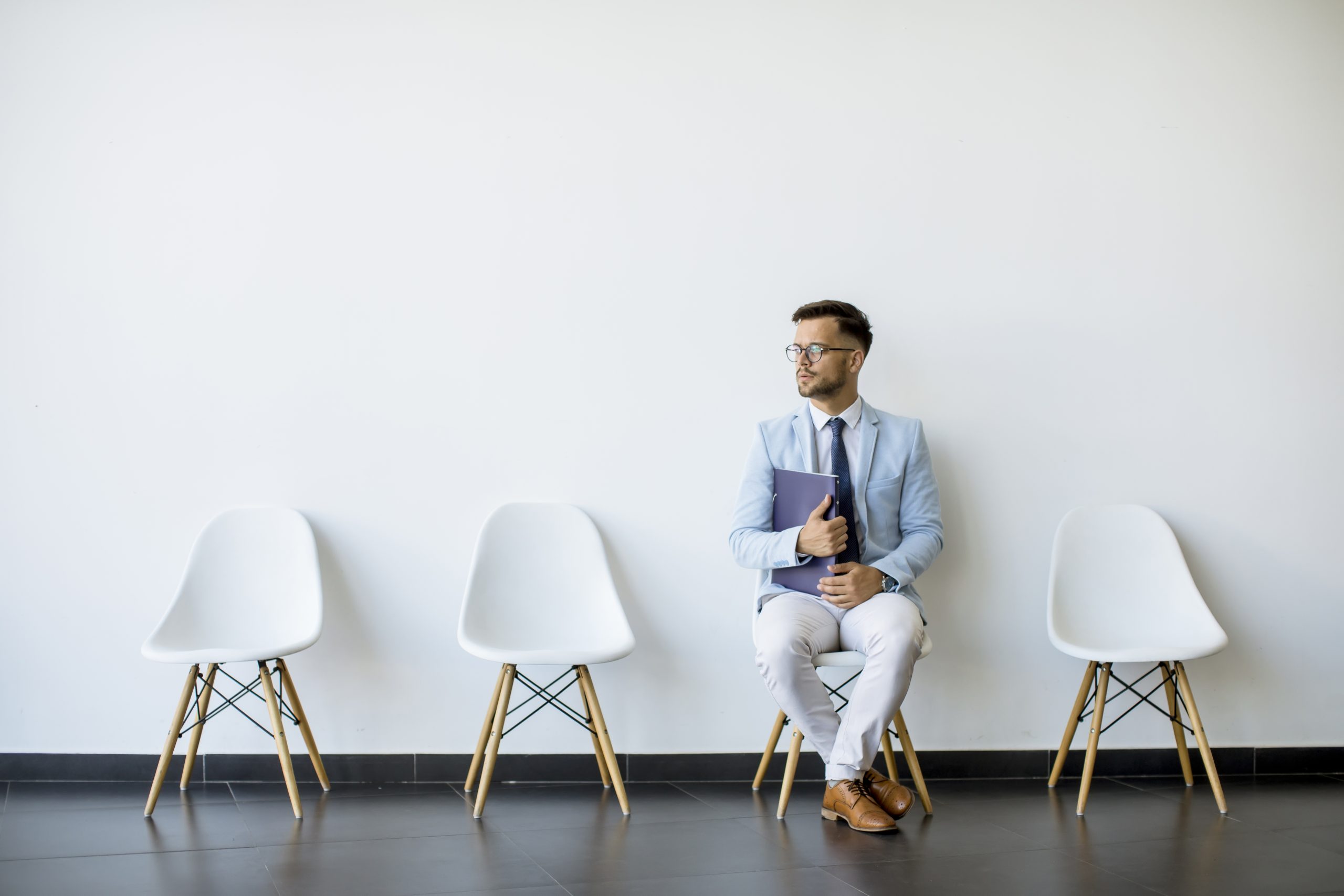 young-man-sitting-in-the-waiting-room-with-folder-in-hand-before-an-interview